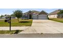 Inviting single-story house with a two-car garage, stone details, a wide driveway, and a mailbox at 1816 Forest Glen Dr, Fruitland Park, FL 34731