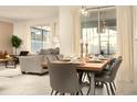 Open-concept dining area with a modern table set for six, adjacent to a living area with a view of the pool at 3009 Penelope Loop, Kissimmee, FL 34746
