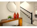 Entryway featuring a wooden console table, decorative vases, round mirror, and a staircase with black railings at 3009 Penelope Loop, Kissimmee, FL 34746