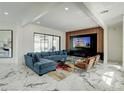 Modern living room with a stylish blue sectional sofa, elegant marble flooring, and a wall-mounted entertainment center at 3532 Amaca Cir, Orlando, FL 32837