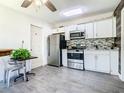 Updated kitchen featuring stainless steel appliances, white cabinetry, and attractive tile backsplash at 5050 Howison Rd, Kissimmee, FL 34746