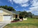 Beautiful home with a lush green lawn, tropical landscaping, and a two-car garage at 8829 Courtyard Ln, Groveland, FL 34736