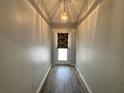 View of a well-lit hallway with wood-look flooring and an elegant pendant light fixture at 8829 Courtyard Ln, Groveland, FL 34736