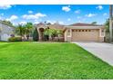 Charming single-story tan home featuring a lush green lawn, manicured landscaping, and a two-car garage at 1585 Maidencane Loop, Oviedo, FL 32765