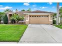 Charming tan home with a lush green lawn, two-car garage, and well-maintained landscaping at 1585 Maidencane Loop, Oviedo, FL 32765