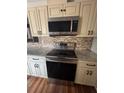 Close-up of a range and over-the-range microwave, with granite countertops and mosaic backsplash at 1603 Gaston Foster Rd, Orlando, FL 32812