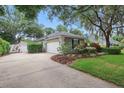 View of the house showing the driveway, garage, and well-maintained lawn with manicured shrubs at 4411 Little Water St, Orlando, FL 32817