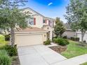 Beautiful two-story home with tan exterior, terracotta roof, and manicured landscaping at 5156 Oakbourne Ave, Davenport, FL 33837
