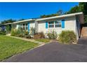 Side view of this single story home with white brick, bright blue shutters, a lush yard, and landscaped flowerbeds at 1118 Ne 17Th Ave, Ocala, FL 34470