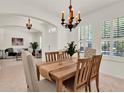 Open-concept dining area adjacent to the living room, featuring a stylish chandelier and plantation shutters at 112 Overton Gardens Lane, Deland, FL 32724