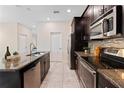 Bright kitchen featuring granite countertops, stainless steel appliances, tile backsplash, and dark cabinets at 11386 Biography Way, Orlando, FL 32832