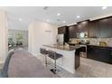 Open kitchen featuring dark wood cabinets, granite countertops, stainless steel appliances, and bar seating at 11386 Biography Way, Orlando, FL 32832