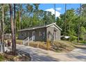 Home featuring a side entrance, concrete walkway, and grill surrounded by trees at 1611 Creekwood Run, Lakeland, FL 33809
