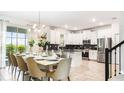 Open-concept kitchen with stainless steel appliances, black backsplash, and a dining area set for a meal at 2916 Simile St, Kissimmee, FL 34746