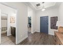 Hallway with wood-look flooring leading to a bathroom and an office area, featuring a gray accent door at 4599 Storytelling Way, Kissimmee, FL 34746
