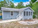Exterior view showcasing the light blue siding, screened porch, and white-trimmed windows and doors at 499 W Beresford Rd, Deland, FL 32720