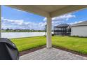 Covered back patio overlooking a tranquil lake view, perfect for outdoor dining and relaxation at 6121 Blue Pond Way, St Cloud, FL 34771