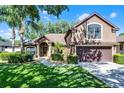 Charming two-story home features manicured landscaping, a two-car garage, and mature palm trees at 1007 Golf View Estates Dr, Orange City, FL 32763