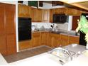 Traditional kitchen with wood cabinets, tiled countertops, and black appliances including oven and microwave at 11624 Delmar Ave, Orlando, FL 32836