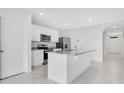 Bright, all-white kitchen featuring granite countertops, stainless steel appliances, and an island at 1312 Sugarwood St, Davenport, FL 33837