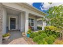 Covered home entrance features a gray door, porch seating and a landscaped garden at 13330 Panama Beach Ct, Orlando, FL 32827