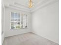Bright, carpeted bedroom with large window, white walls, ceiling trim, and gold chandelier at 212 Tavestock Loop, Winter Springs, FL 32708