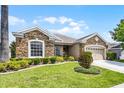 Beautiful single-story home with stone detailing, lush green lawn, and mature trees on a sunny day at 212 Tavestock Loop, Winter Springs, FL 32708