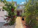 Inviting front entrance with tiled walkway and vibrant landscaping leading to a striking red front door at 2530 Baykal Dr, Kissimmee, FL 34746