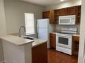 Functional kitchen with modern white appliances, wood cabinets, and a convenient breakfast bar at 4001 San Sabastian Dr # 107, Kissimmee, FL 34741