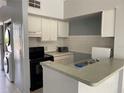 Efficient kitchen layout featuring white cabinetry, black appliances, and a pass-through counter at 4001 San Sabastian Dr # 107, Kissimmee, FL 34741