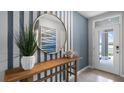 A modern entryway featuring blue striped walls, a wood table, round mirror, and decorative accents at 408 Taylor Groves Dr, Lake Wales, FL 33853