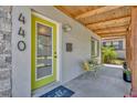 Inviting front porch with natural wood accents, decorative chairs and a vibrant green door at 440 E Crystal Lake St, Orlando, FL 32806