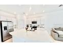 Modern kitchen with white cabinetry, stainless steel appliances, a quartz countertop island, and an open view of the living area at 4520 Calvary Way, St Cloud, FL 34769