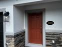 Home's front door with stone accents, modern lighting, and clearly visible address number at 5099 Prairie Preserve Run, St Cloud, FL 34772