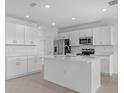 Bright open-concept kitchen with stainless steel appliances, white cabinets, a kitchen island, and recessed lighting at 5109 Forget Me Not Ave, Lake Hamilton, FL 33851