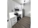 Modern kitchen with white cabinets, stainless steel appliances, and stylish light fixture at 7147 Yacht Basin Ave # 119, Orlando, FL 32835