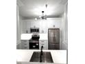 Bright kitchen featuring modern white cabinets, stainless steel appliances and black hardware at 7147 Yacht Basin Ave # 119, Orlando, FL 32835