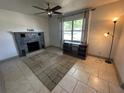 Cozy living room featuring a stone fireplace, neutral tile flooring, and bright window at 890 Emerald Dr, Mount Dora, FL 32757