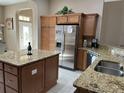 Kitchen featuring granite countertops, stainless steel appliances, and brown cabinetry for ample storage at 11120 Se 168Th Loop, Summerfield, FL 34491