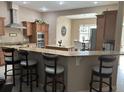 Kitchen with a breakfast bar overlooking the dining room, stainless steel appliances, and brown cabinetry at 11120 Se 168Th Loop, Summerfield, FL 34491