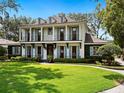 Elegant home featuring an expansive lawn, a second-story balcony, and contrasting light blue shutters for a stylish look at 1400 Place Picardy, Winter Park, FL 32789