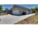 Exterior showcasing the home's side and driveway, complete with trash receptacles and side-entry door at 2300 Dawnwood Ln, Orlando, FL 32809