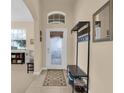 Bright foyer featuring neutral walls, tiled flooring, coat rack, a decorative rug, and a front door with decorative glass at 23520 San Sebastian Ct, Sorrento, FL 32776