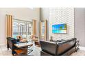 Bright living room with high ceilings, brick accent wall, stylish furniture, and sliding doors to the pool area at 2791 Punctuation Pl, Kissimmee, FL 34746
