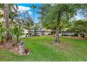 Beautifully landscaped front yard featuring a lush green lawn, mature trees, and charming decorative elements at 311 Needles Trl, Longwood, FL 32779