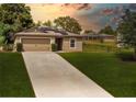 Charming single-story home with an attached garage, solar panels, and well-maintained lawn at sunset at 543 Nardello Dr, Deltona, FL 32725