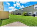 View of backyards of townhomes featuring green lawns, small patios, and mature trees at 725 Cresting Oak Cir # 117, Orlando, FL 32824