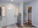 Bright foyer featuring a white door, decorative rug, modern flooring, and staircase leading to the upper level at 7254 Della Dr, Orlando, FL 32819