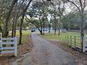 Long paved driveway leads to this country estate with a white fenced in yard and mature trees at 16742 Se 165Th Ave, Weirsdale, FL 32195