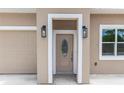 Close-up showcasing an inviting front door with decorative glass and stylish lanterns on the neutral facade at 2065 East Pkwy, Deland, FL 32724